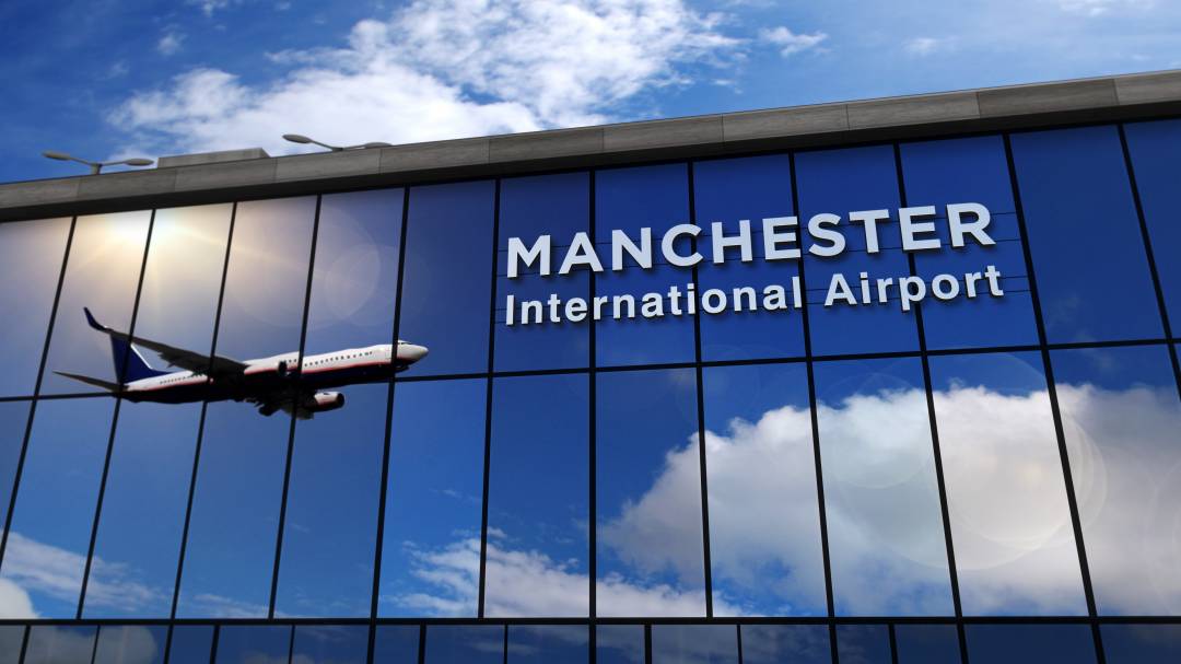 Picture of Manchester Airport terminal building with a plan taking off reflecting off the windows